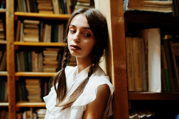 Meisje met staartjes in witte blouse bij oude bibliotheek