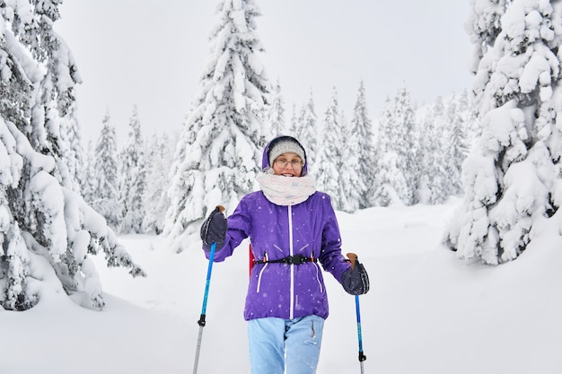 Meisje met stokken voor trekking in het besneeuwde winterbos