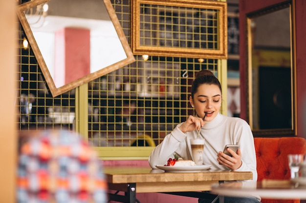 Meisje met telefoon koffie drinken in een café