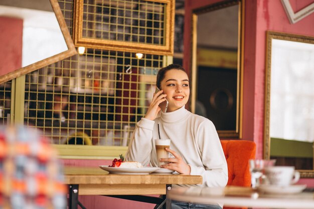 Meisje met telefoon koffie drinken in een café