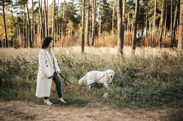 Meisje met witte gouden retrieverhond op het bospad