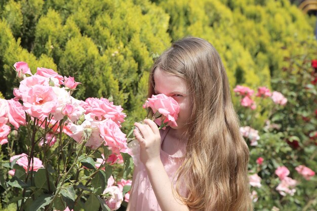 Foto meisje onder bloembed van roze rozen