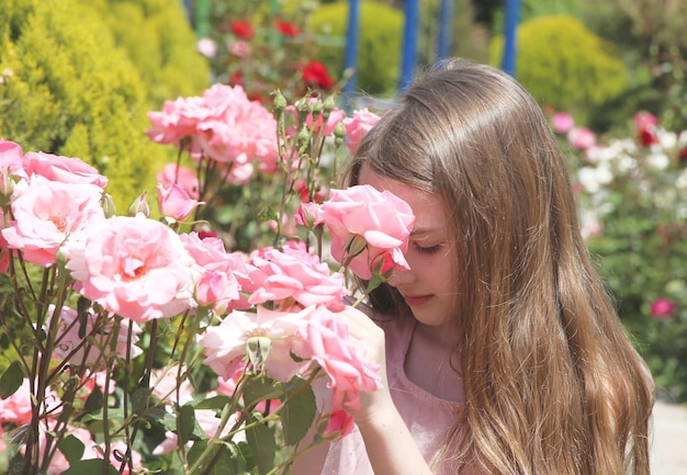 Meisje onder bloembed van roze rozen