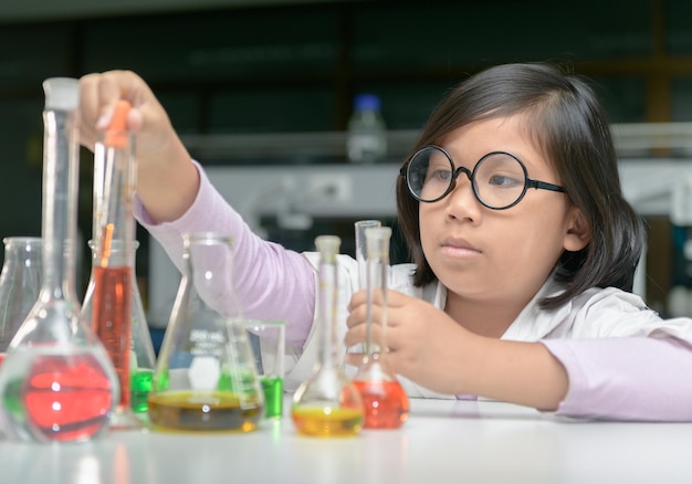 Meisje onderzoekt chemicaliën in het laboratorium.