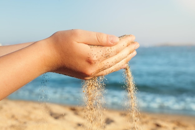 Meisje ontspannen op zee strand Zand vallen uit de vrouwelijke handen op zee strand achtergrond