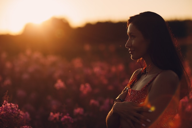 Meisje op bloeiend Sally-bloemgebied bij zonsondergang. Lila bloemen en vrouw.