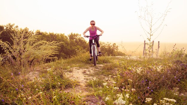 Meisje op de mountainbike rijdt op het parcours op een prachtige zonsopgang.