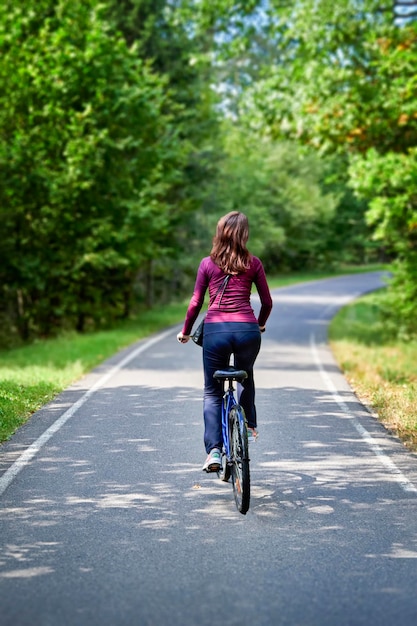 Meisje op een fiets rijdt door een zomerpark Achteraanzicht