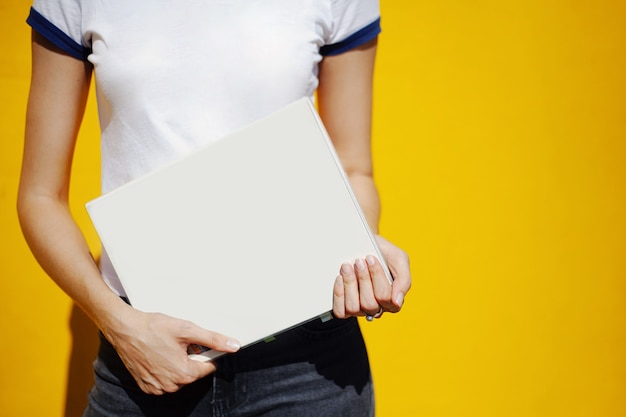 Meisje op een gele muur met een groot notitieboekje met een blanco omslag