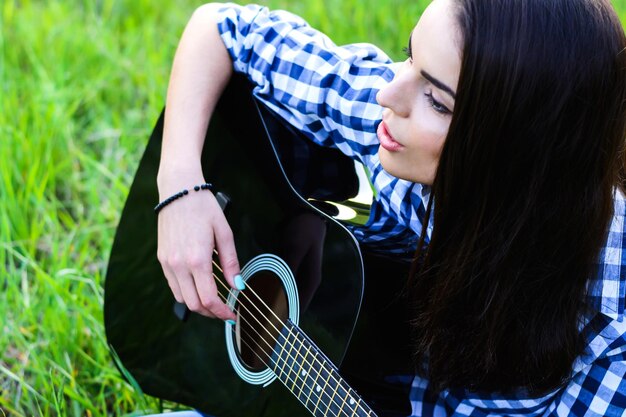 Meisje op een groene weide die gitaar speelt