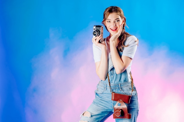 Meisje op een koffer met een camera op een blauwe achtergrond die op vakantie, toerismeconcept gaat