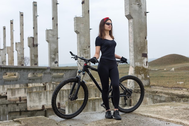 Meisje op een mountainbike op offroad mooi portret van een fietser in regenachtig weer Fitness meisje rijdt op een moderne koolstofvezel mountainbike in sportkleding Close-up portret van een meisje in rode bandana