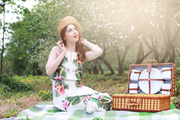 Meisje op een picknick in de appelboomgaard met een mand met producten