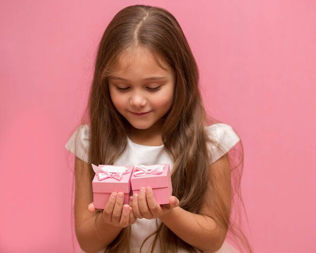 Meisje op een roze achtergrond met geschenkdozen