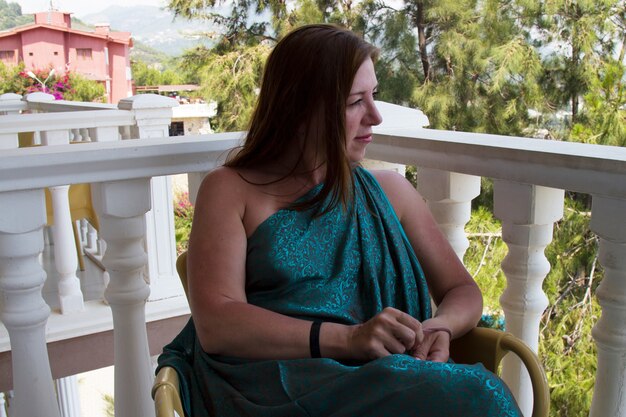 Meisje op het balkon kijkend naar de lucht. een roodharige vrouw met groene ogen en een groene jurk. een vakantie in het zuiden