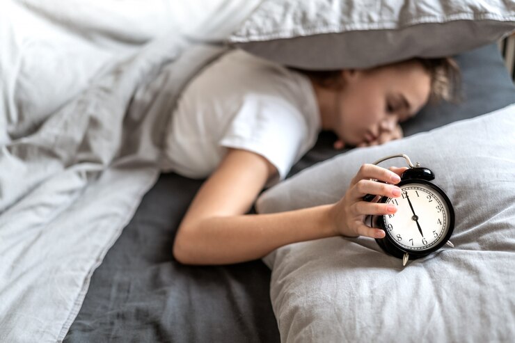 meisje op het bed dat de wekker uitzet