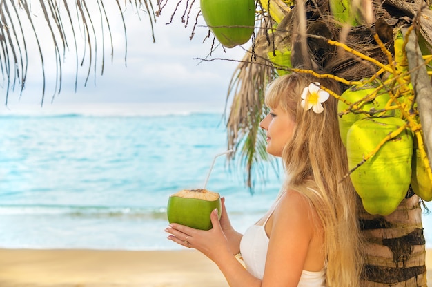 Foto meisje op het strand drinkt kokosnoot.