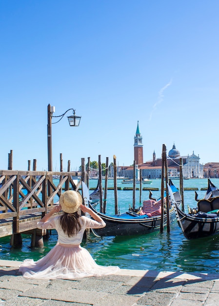 Foto meisje op ligplaats met gondels in venetië