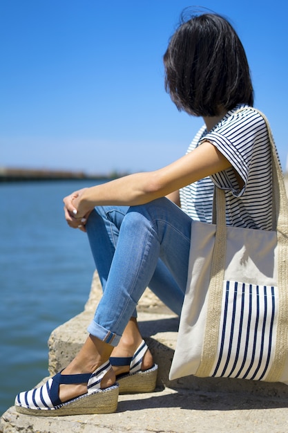 Meisje op vakantie op het strand met zomerse casual outfit en een tas