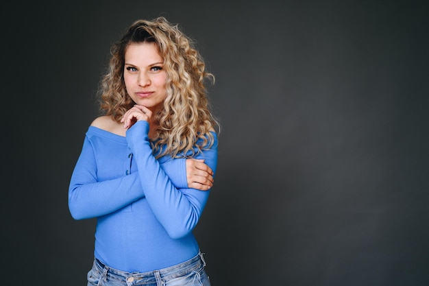 Meisje op zwarte muur in blauwe jas vouwde haar handen op haar borst Vrouw maakt weloverwogen keuze