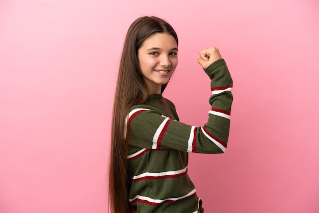 Meisje over geïsoleerde roze muur die sterk gebaar doet