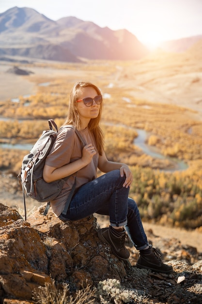 Meisje reiziger toerist zit op steen op de achtergrond van de natuur