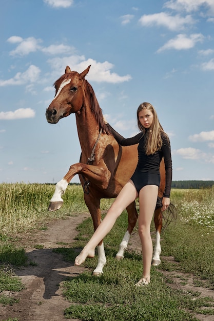 Meisje rijder staat naast het paard in het veld