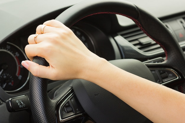 Meisje rijdt in een auto, houdt het stuur met één hand vast