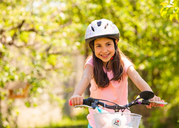Meisje rijdt op de fiets met haar speelgoed in de mand Zomeractiviteit