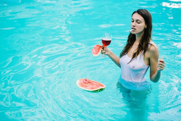 Meisje roken met watermeloen en wijn in zwembad