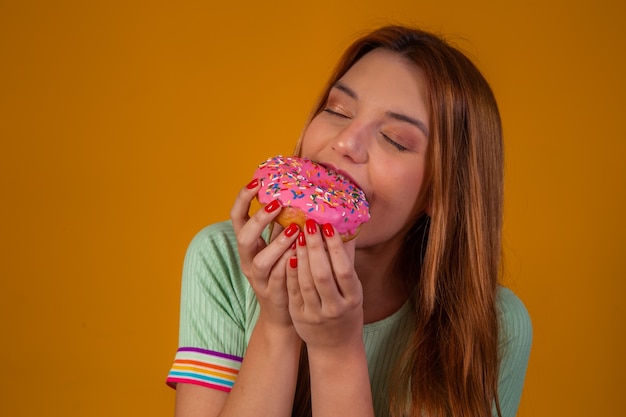 Meisje roze donuts eten op gele achtergrond.