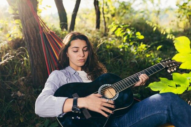 meisje rusten in een hangmat met een gitaar in het park