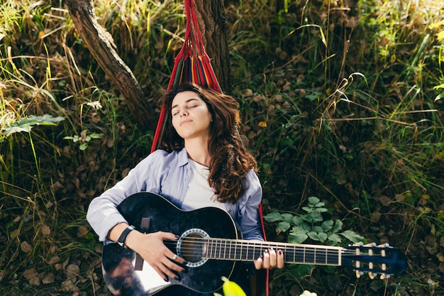 meisje rusten in een hangmat met een gitaar in het park