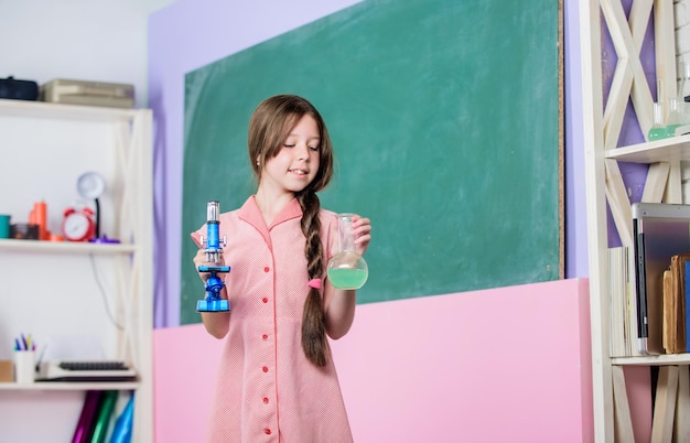 Meisje scheikunde les reageerbuis Klein meisje met chemische buis Biologie onderwijs Chemische reactie Chemische vloeistof Fascinerende les Wetenschapsles School laboratorium Wetenschappelijk experiment