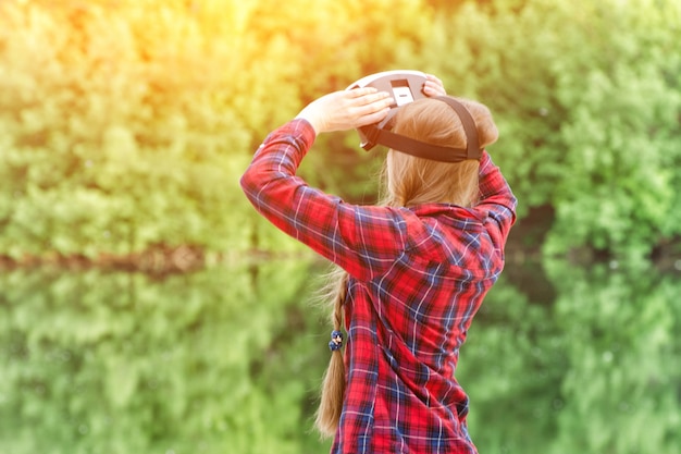 Meisje schiet VR-bril, zonsondergang in de natuur, uitzicht vanaf de achterkant