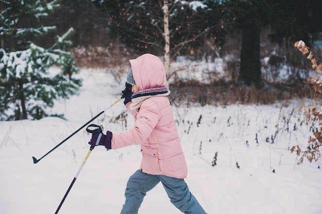Meisje skiet op een met sneeuw bedekt veld tegen naakte bomen