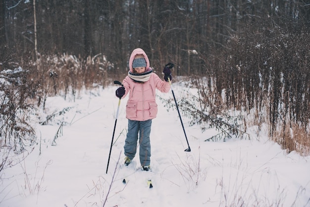 Meisje skiet op een met sneeuw bedekt veld tegen naakte bomen