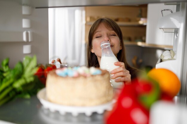 Meisje snuift melk uit de fles die ze in de koelkast heeft genomen