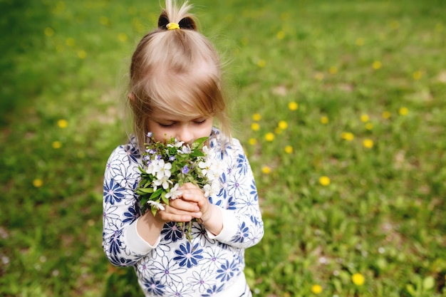 Meisje snuiven Lentebloemen op groen gazon in de tuin