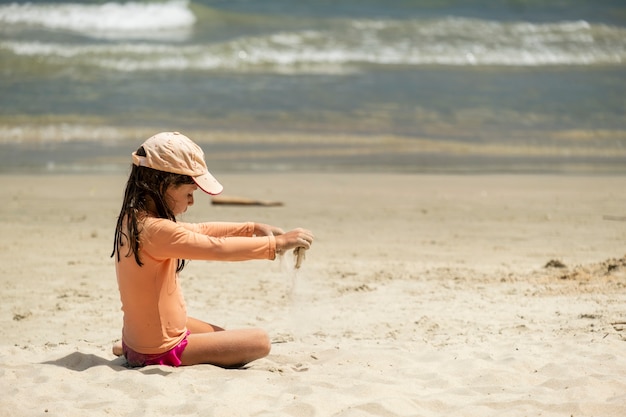 Meisje speelt alleen zittend op het strandzand.