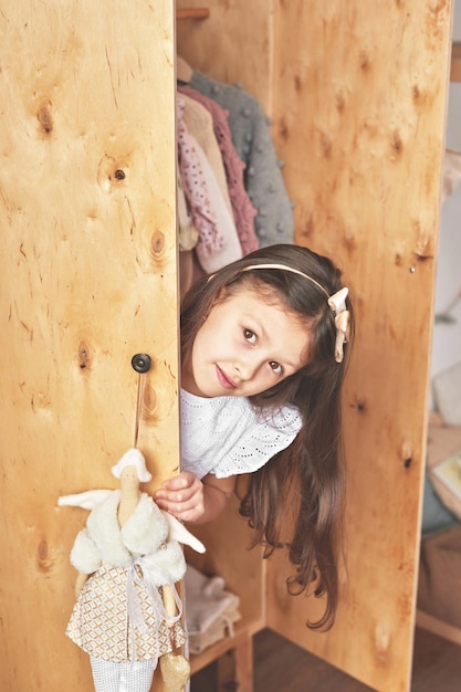 Meisje speelt in de speelkamer van de kinderen Scandinavische kinderkamer Houten speelgoed en decor