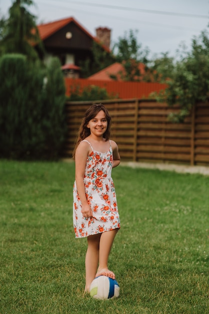 Meisje speelt met de bal in de tuin. Zomervakantie.