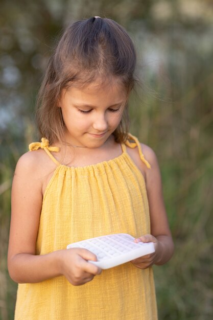 Meisje speelt met een speeltje pop it, in de natuur