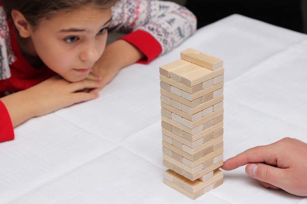 Meisje speelt met haar vader het bouwen van een toren van houten blokken