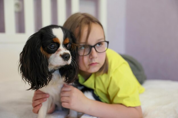 Meisje speelt met hond king charles spaniel op lichte achtergrond, zachte focus