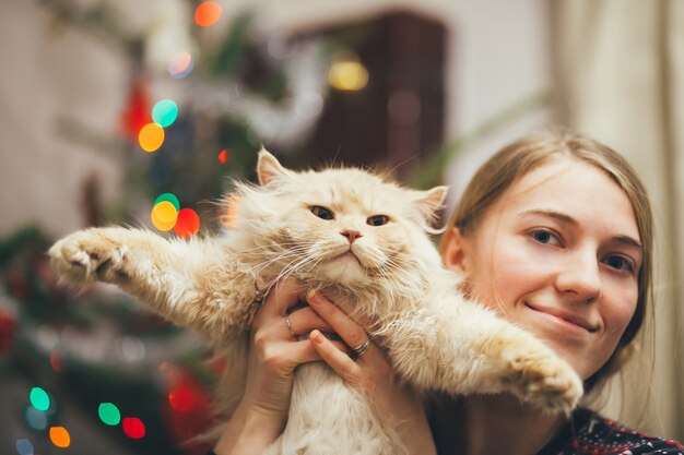 meisje speelt met kat op kerstboom achtergrond