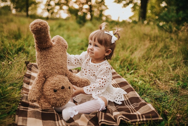 Meisje speelt met teddybeer in het bos