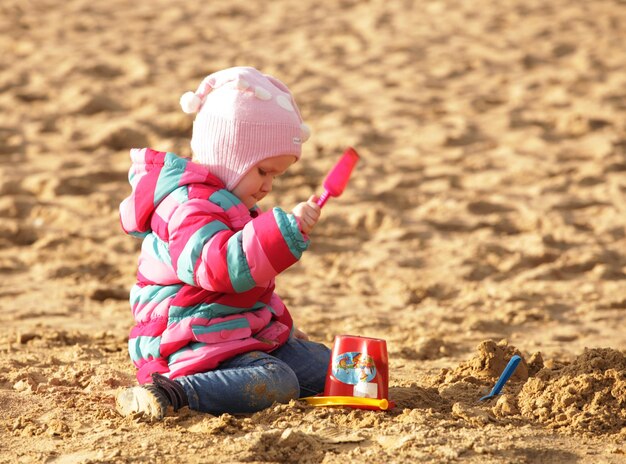 Meisje speelt met zand op het herfststrand