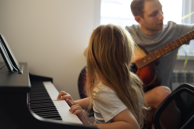 Foto meisje speelt piano terwijl ze thuis bij haar vader zit.