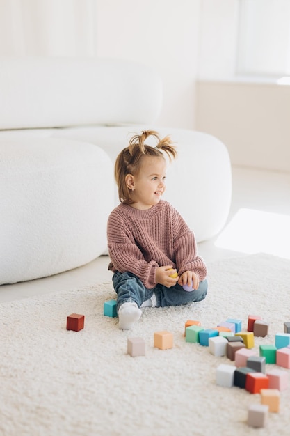 Meisje speelt speelgoed in de woonkamer Montessori houten speelgoed gevouwen piramide cirkel driehoek rechthoek houten elementen van children39s speelgoed gekleurd speelgoed blauw geel rood groen